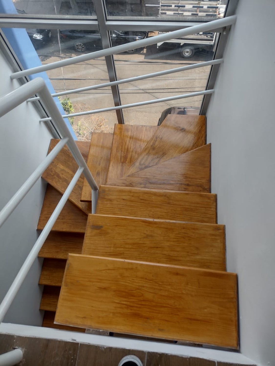 Escalera con peldaños de madera y barandal metálico en una vivienda