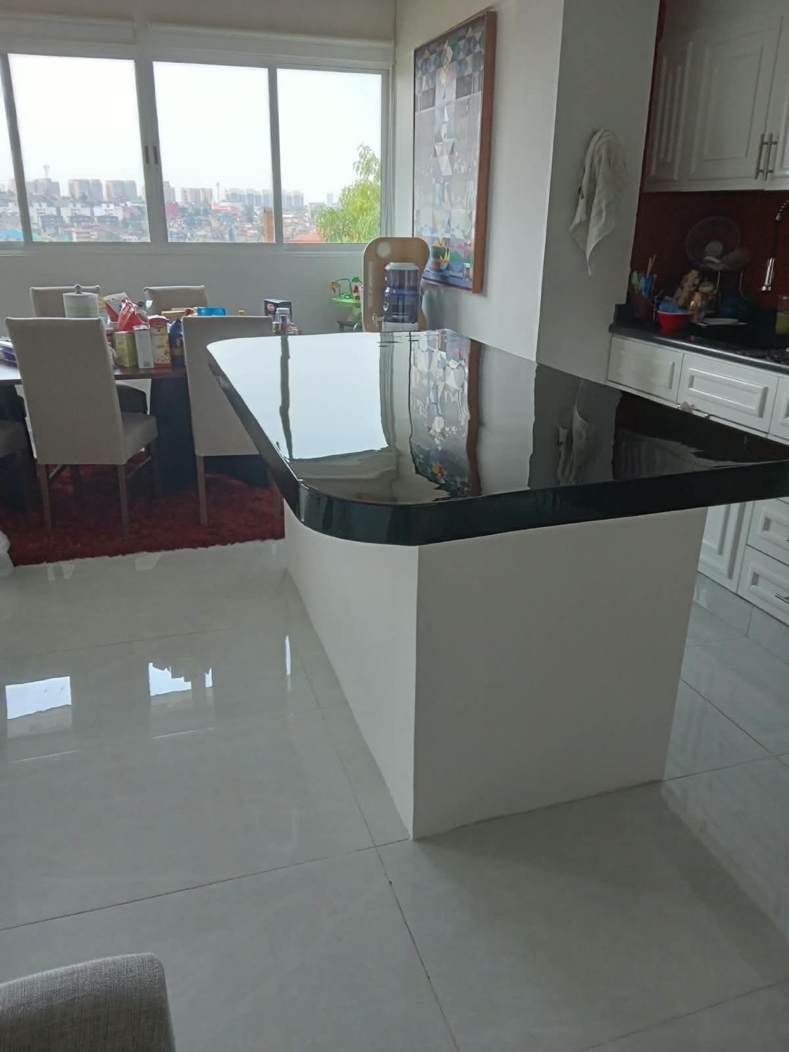 Cocina con barra de granito y piso porcelánico en un departamento remodelado