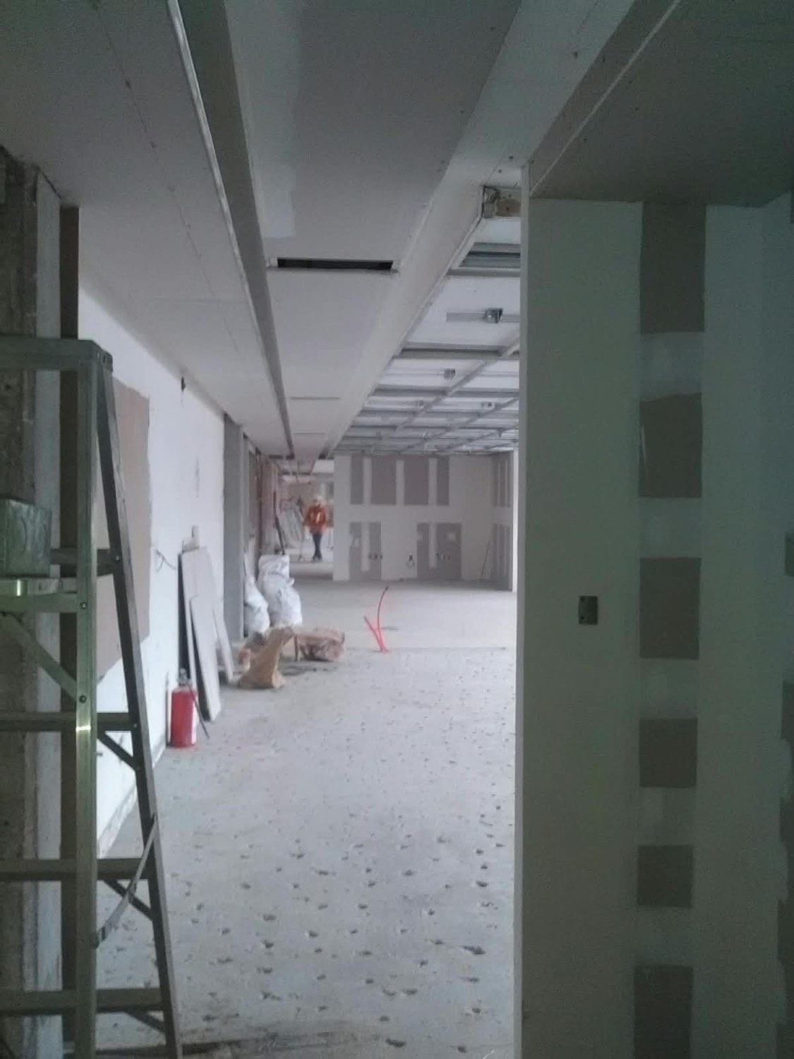 Pasillo de oficinas con muros de tablarroca y plafón en proceso