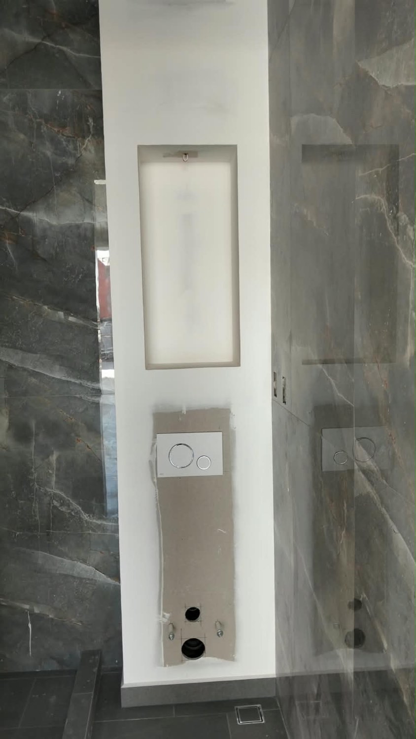 Baño con recubrimiento porcelánico tipo mármol y nicho en el muro