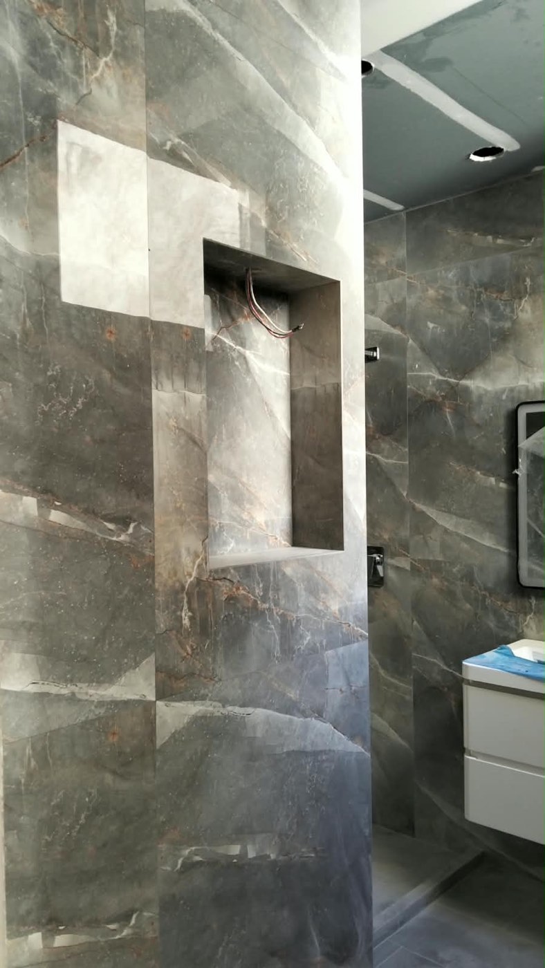 Baño terminado con muros de porcelánico tipo mármol y nicho